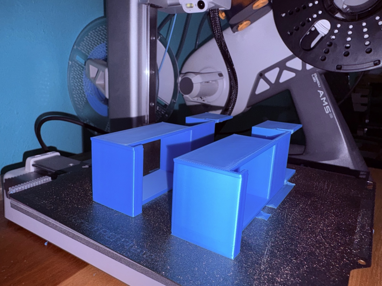 Several blue 3D printed enclosures finished on the printer's build plate